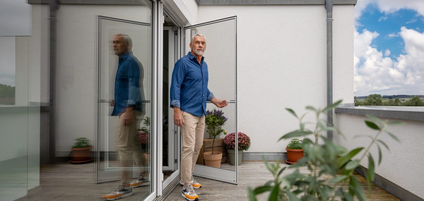 Frau mit braunen Haaren steht am offenen Fenster und setzt einen Spannrahmen ein.